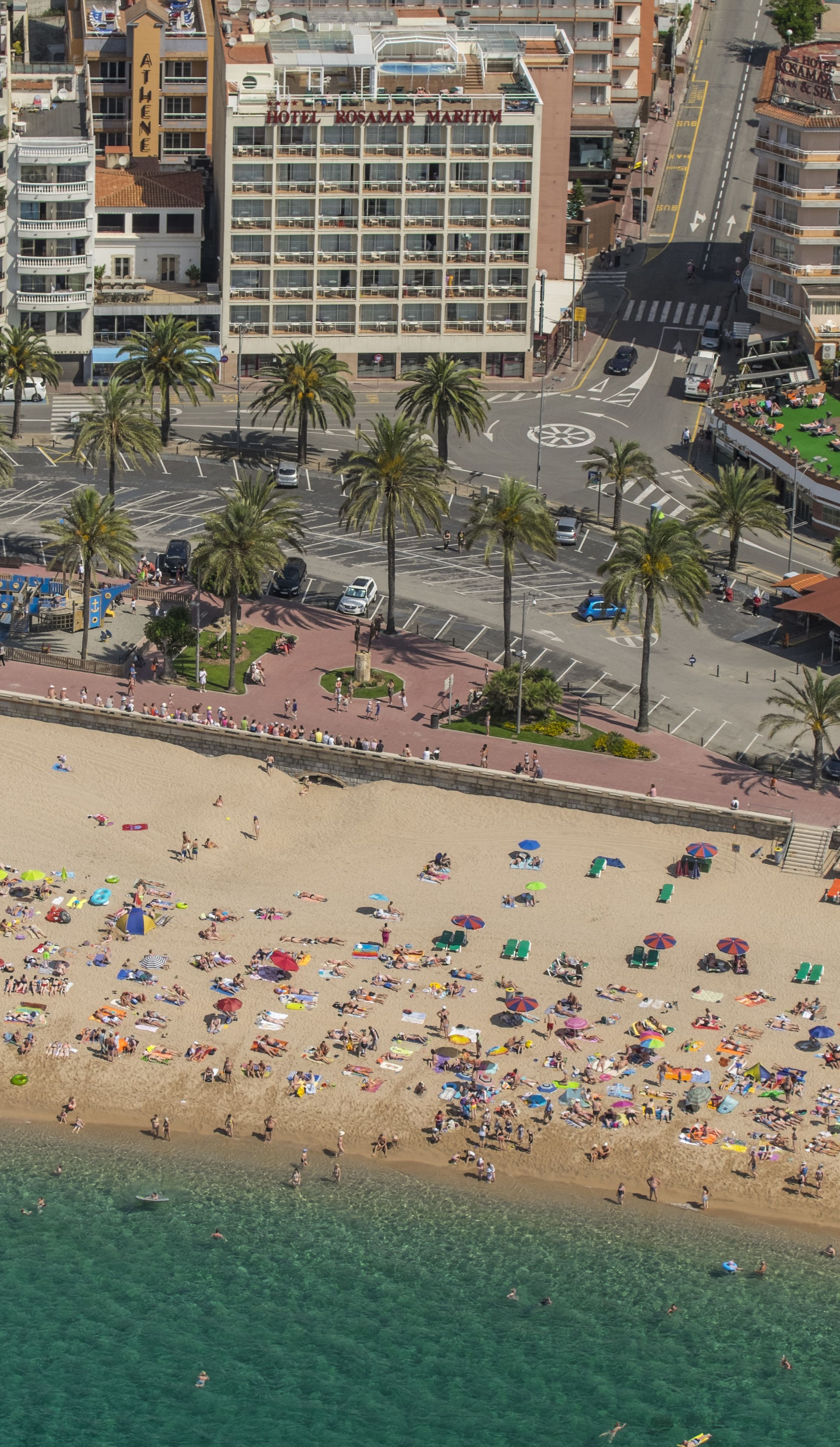 Un hotel con piscina en la azotea y una playa al frente.