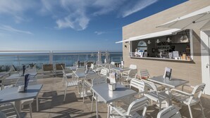 Een restaurant aan de kust met terras, een bar en uitzicht op de oceaan.