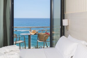 A hotel room with a balcony overlooking the sea, featuring a bed, a table with chairs, and a view of the ocean. - Hotel Marsol (Lloret de Mar)