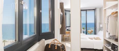 Una habitación de hotel con un ventanal grande, una cama, un escritorio y un armario.
