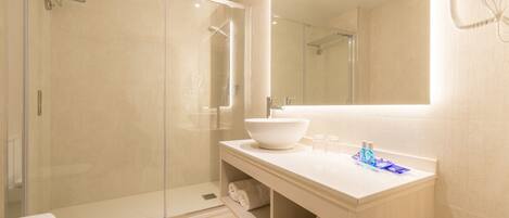 Un baño moderno con ducha envuelta en vidrio, un lavabo blanco de gran tamaño y un espejo sobre el lavabo.