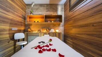 Relax in a serene spa setting with a massage table, candles, and a peaceful ambiance.