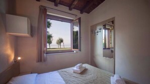 Une chambre à coucher avec un lit, une fenêtre donnant sur un beau paysage, une table de chevet et un miroir.