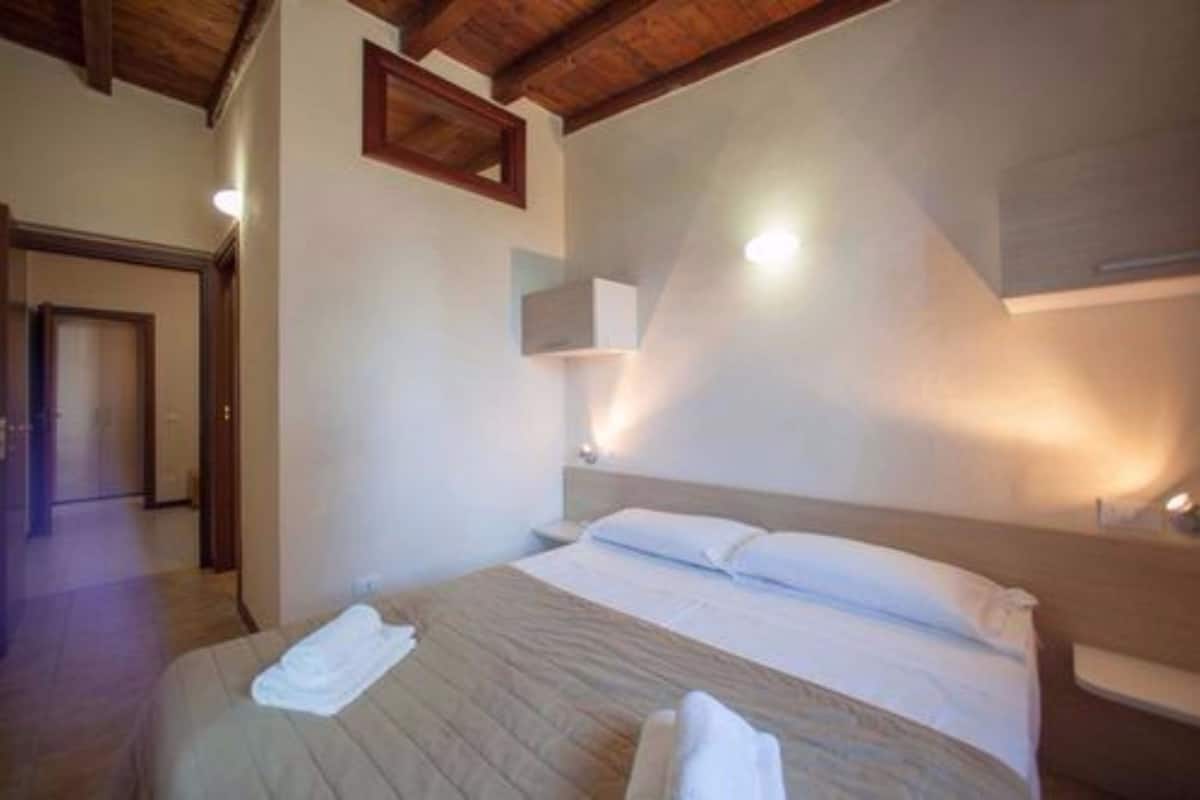 Ein Schlafzimmer mit Holzbalkendecke, einem Bett mit weißen Bettwäsche und einem Nachttisch.