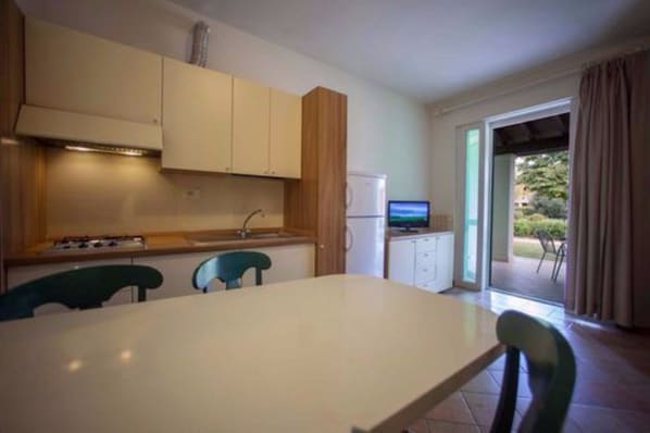 Una cocina funcional con una mesa, sillas y un refrigerador pequeño.