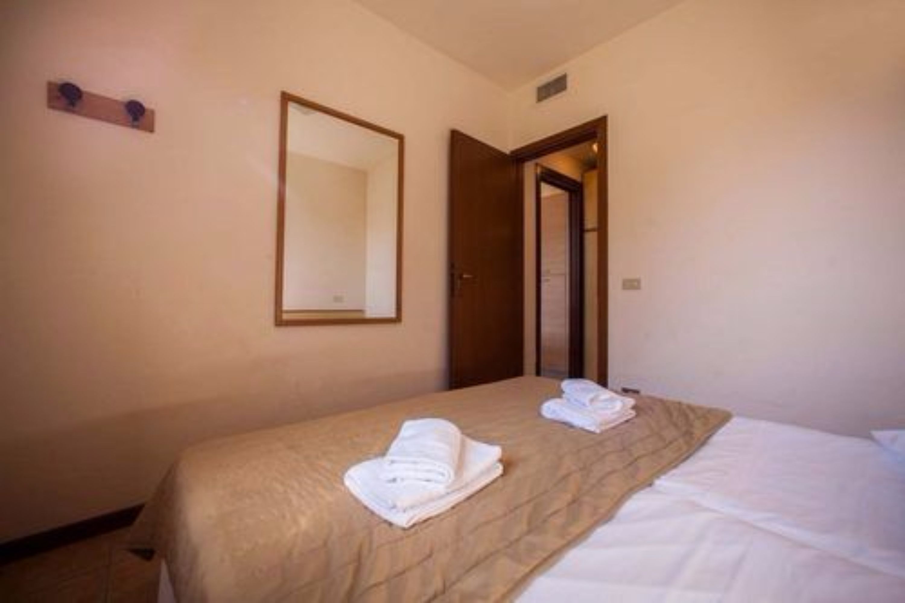 A hotel room with a bed, a mirror, and a door.