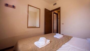 A hotel room with a bed, a mirror, and a door.
