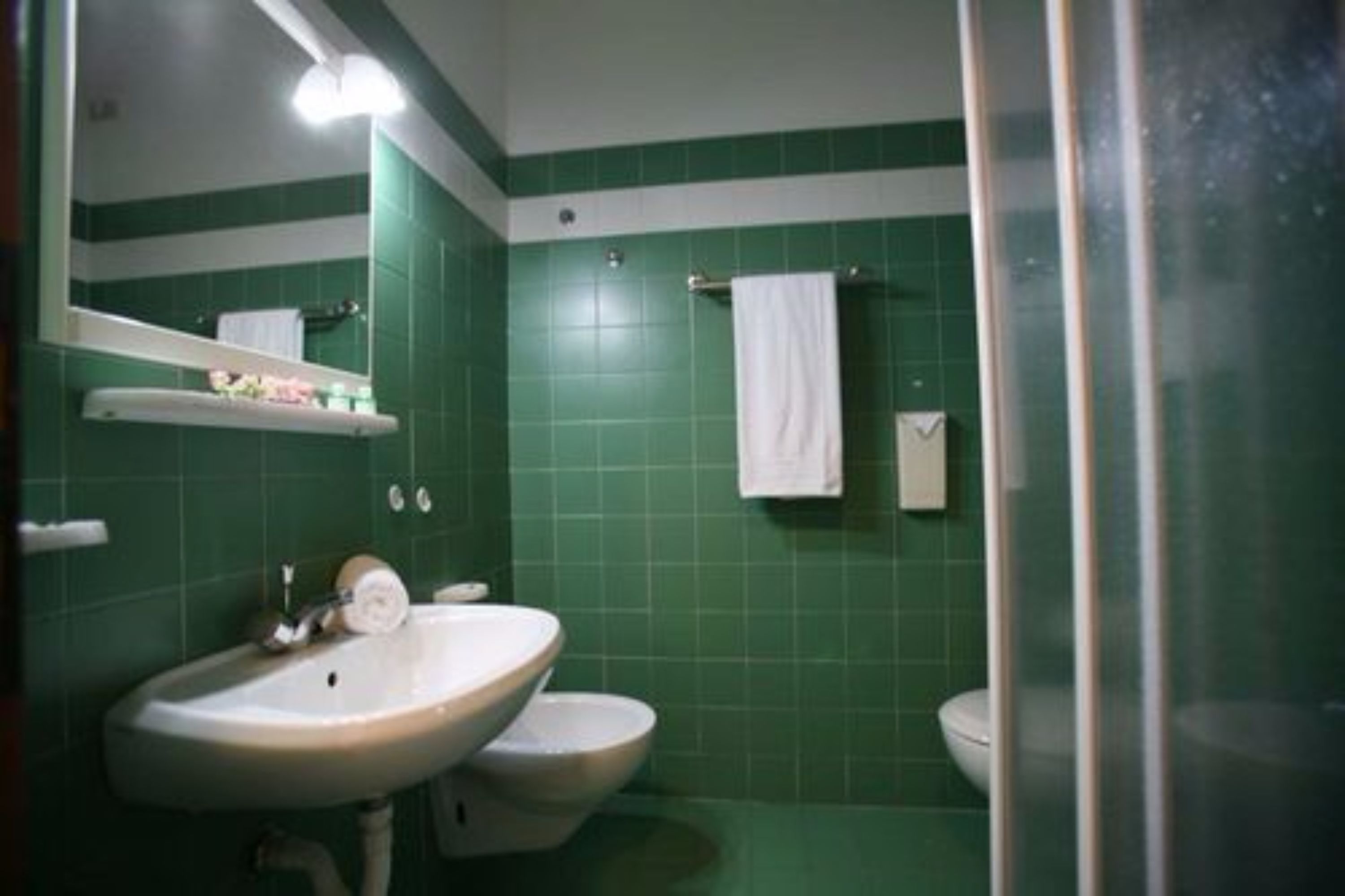 Een badkamer met een wastafel, twee toiletten en een spiegel.