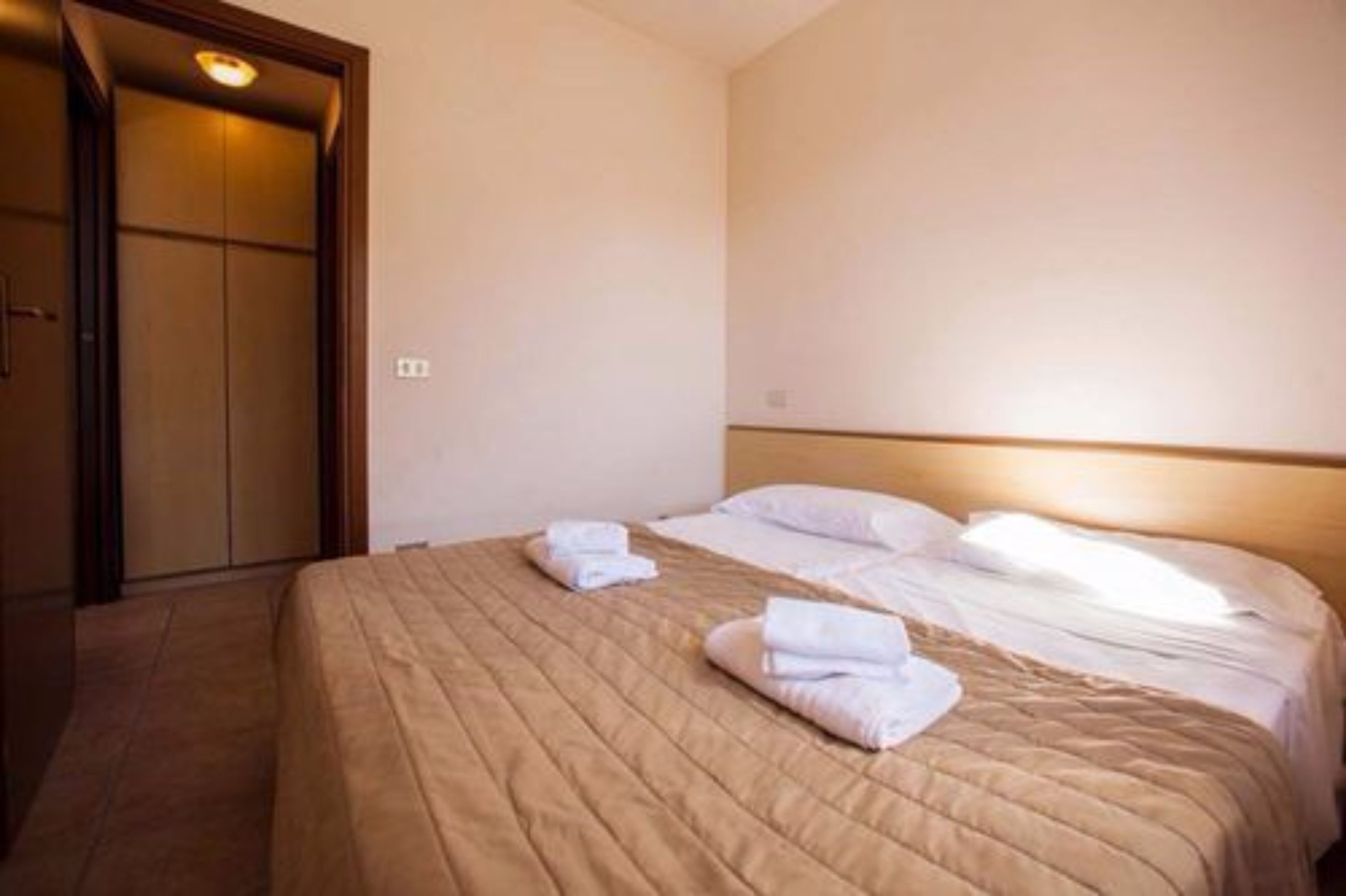 A hotel room with a bed, pillows, and neatly folded towels.