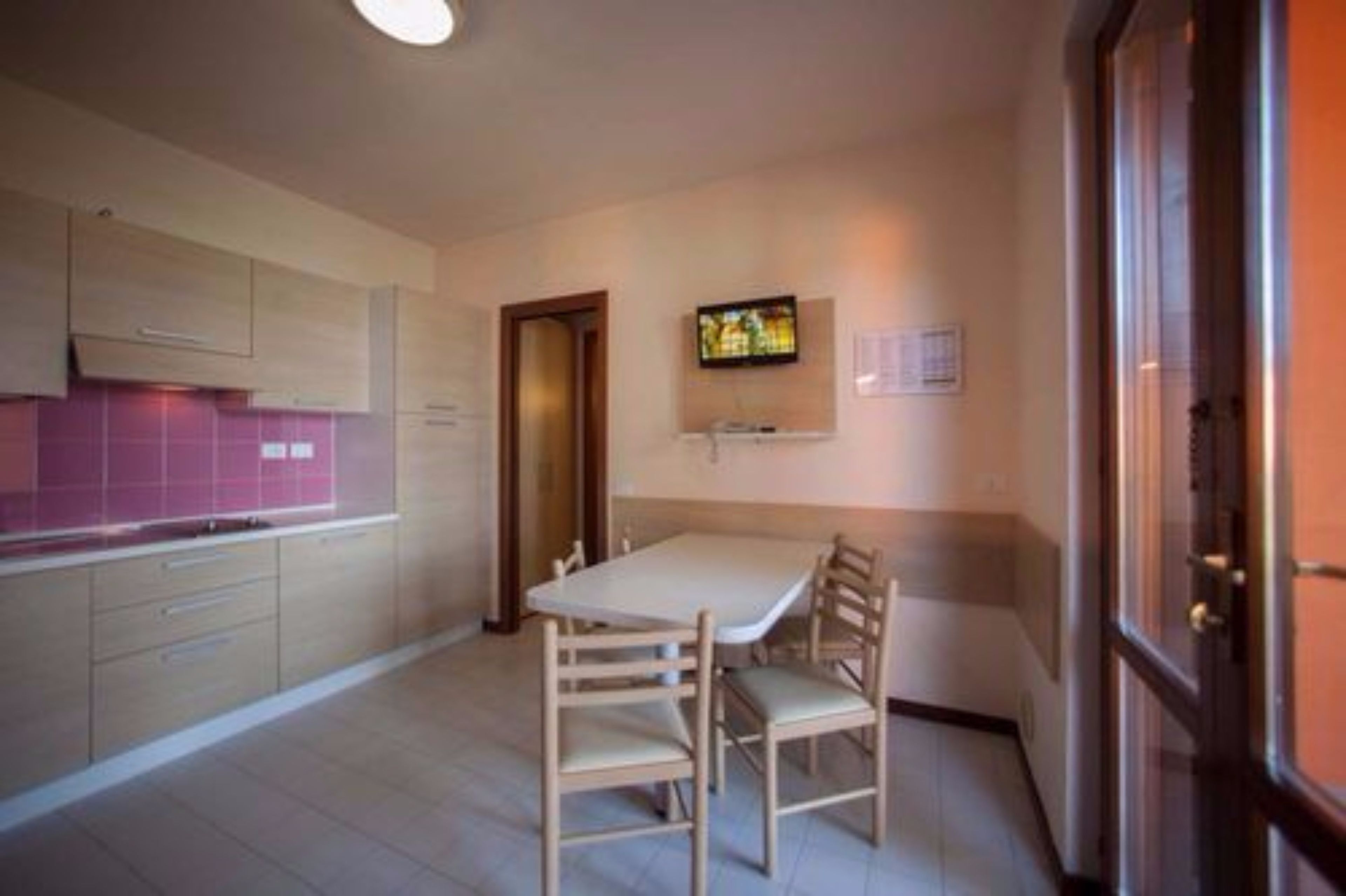 Une cuisine de taille réduite, comprenant une table et des chaises pour les repas, une petite fenêtre et une porte donnant sur une autre pièce.