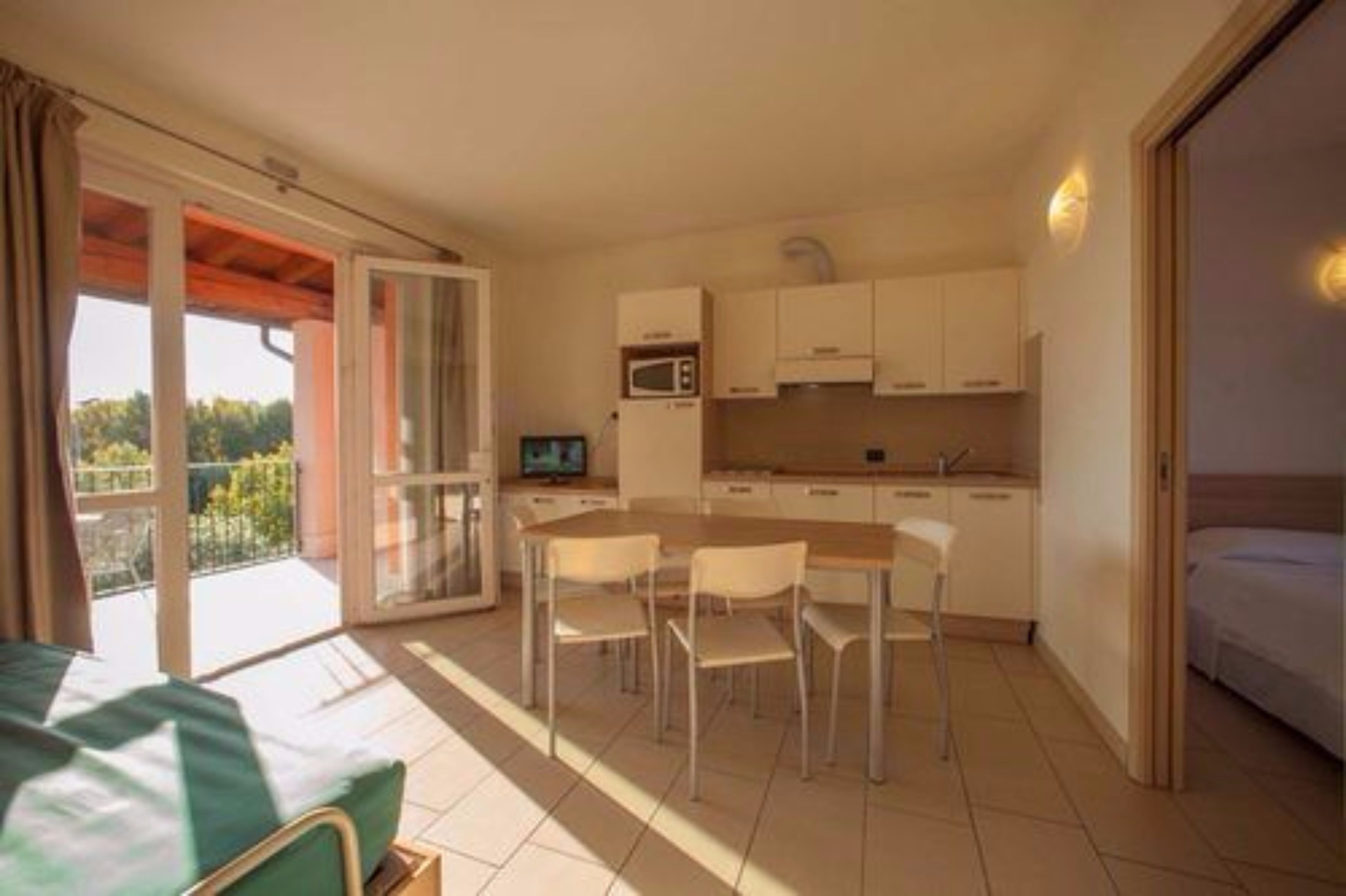 A compact kitchen with a dining area, a TV, and a balcony with a view.