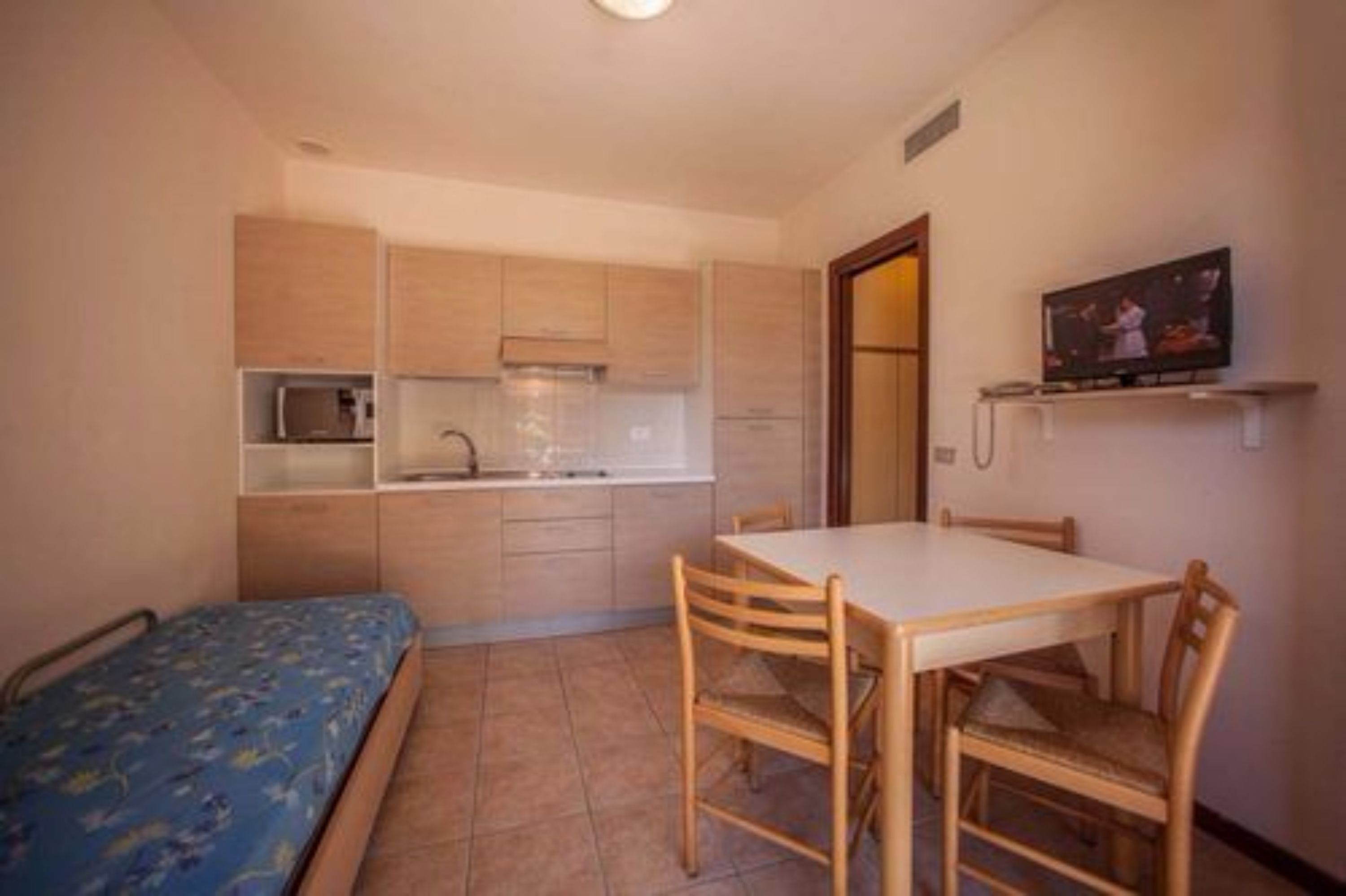 A compact kitchen with wooden cabinets, a microwave, and a small dining table with chairs.