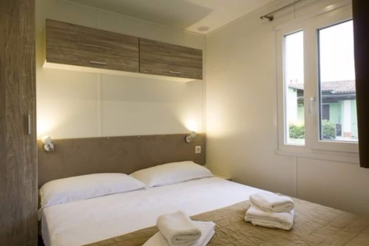Ein Hotelzimmer mit Bett, Fenster und einem Holzkopfteil.