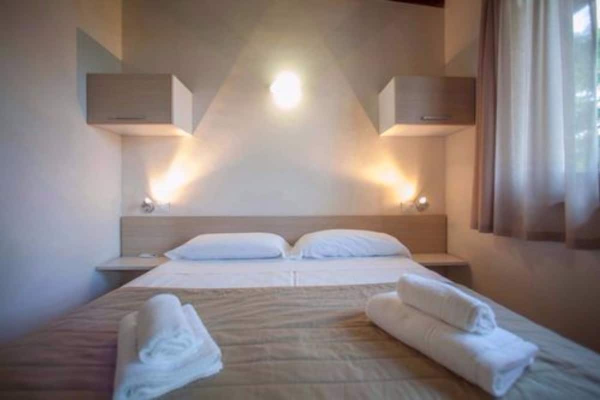 Ein Hotelzimmer mit einem großen Bett, zwei Nachttischen und einem Kopfteil mit integrierter Beleuchtung.