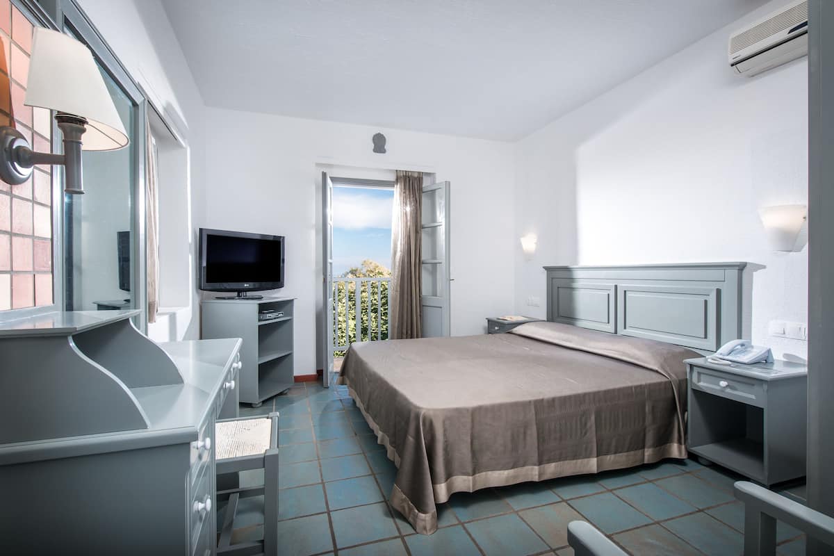 Une chambre d’hôtel équipée d’un lit, d’un bureau, d’une télévision et d’une fenêtre donnant sur un paysage agréable.