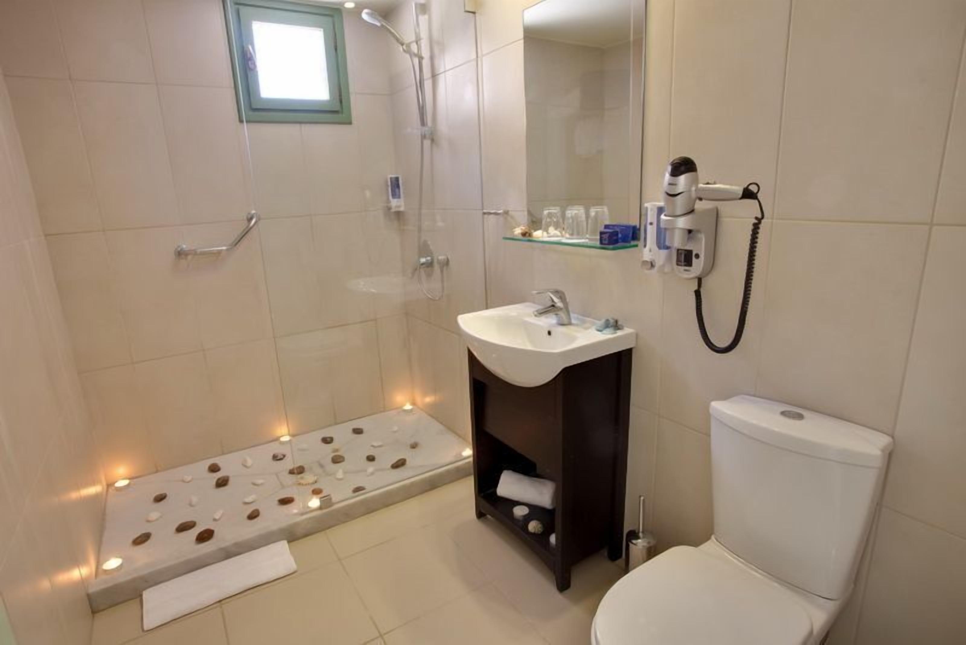 A modern bathroom with a shower, toilet, sink, and a small shelf with toiletries.