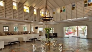 A spacious lobby with a high ceiling, a central glass table, and a hanging light fixture. - Silva Beach Hotel (Hersonissos)