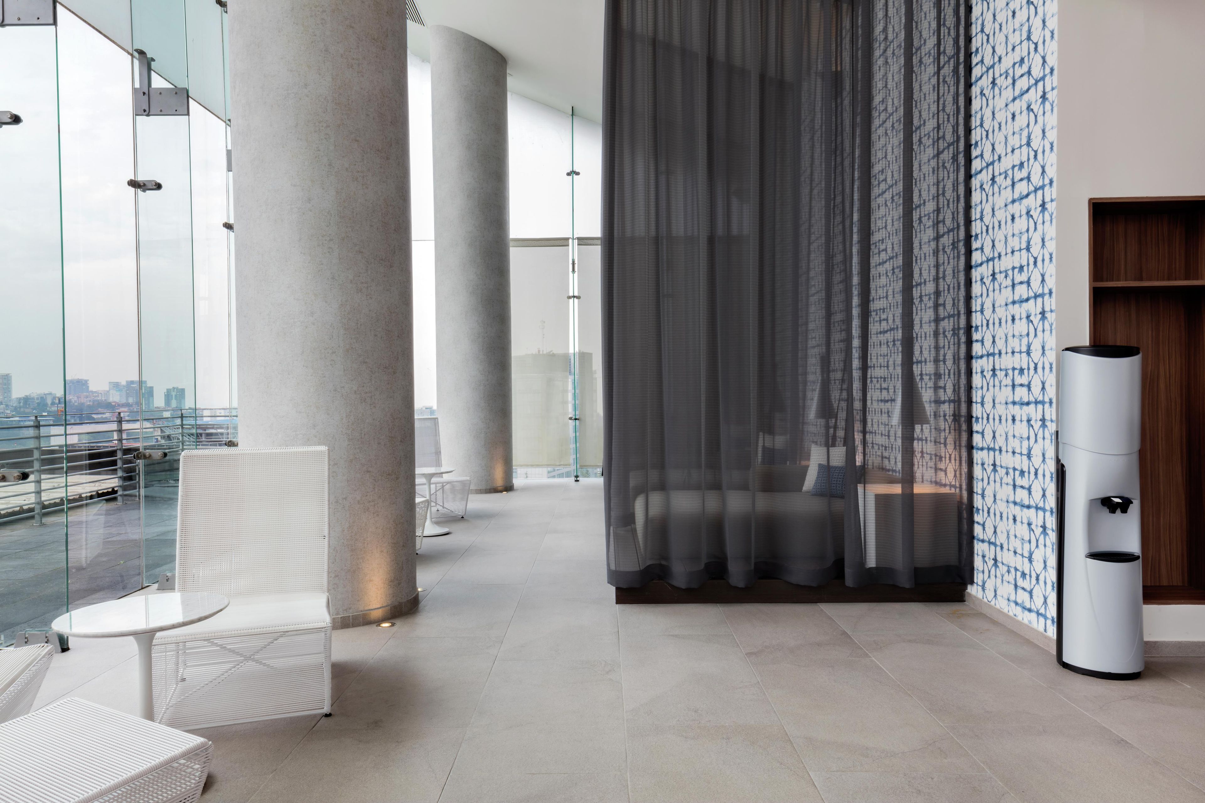 A modern interior with a glass railing, white furniture, and a city view.