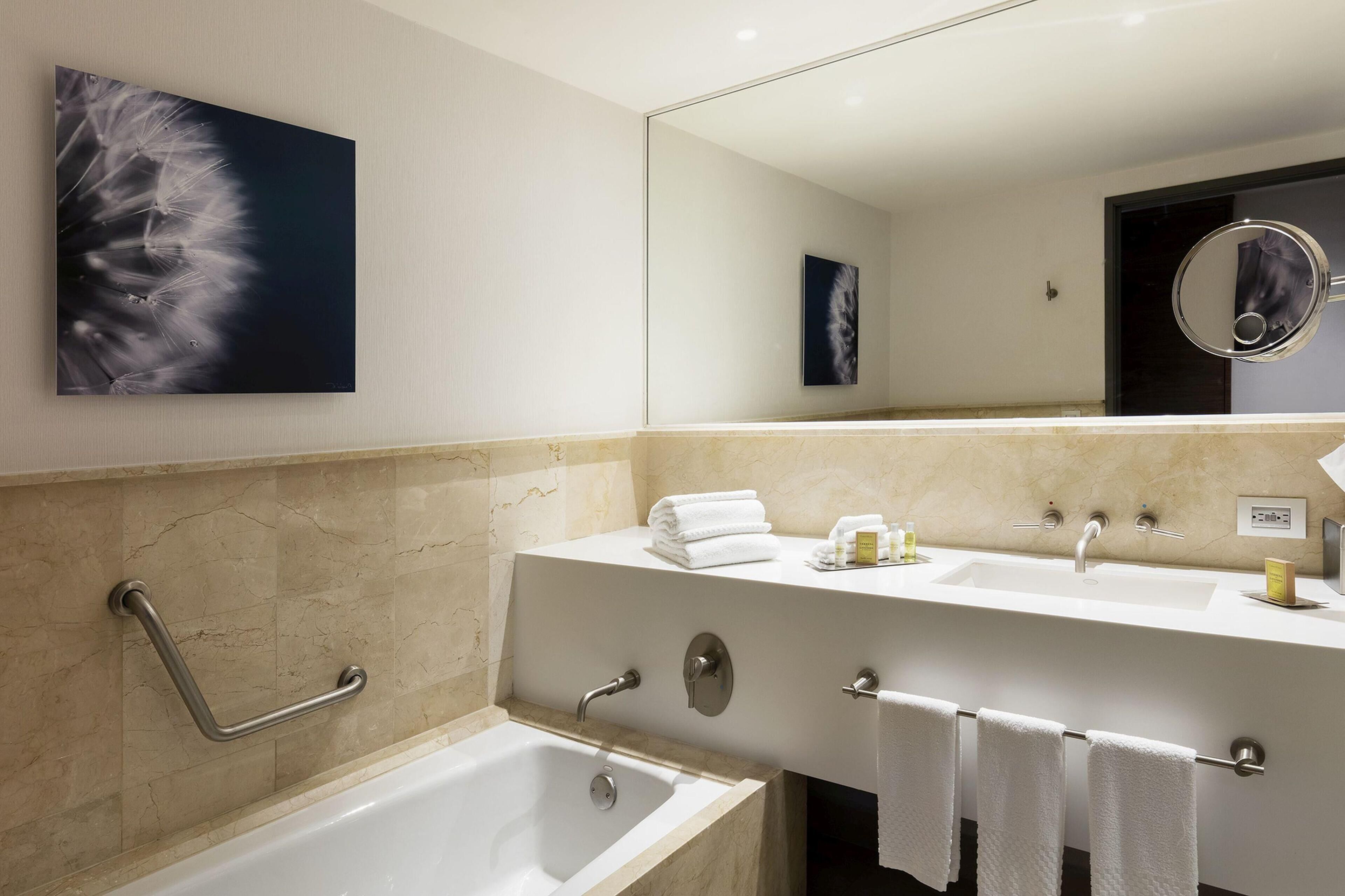 A modern bathroom with a bathtub, a vanity with a mirror, and a towel rack.