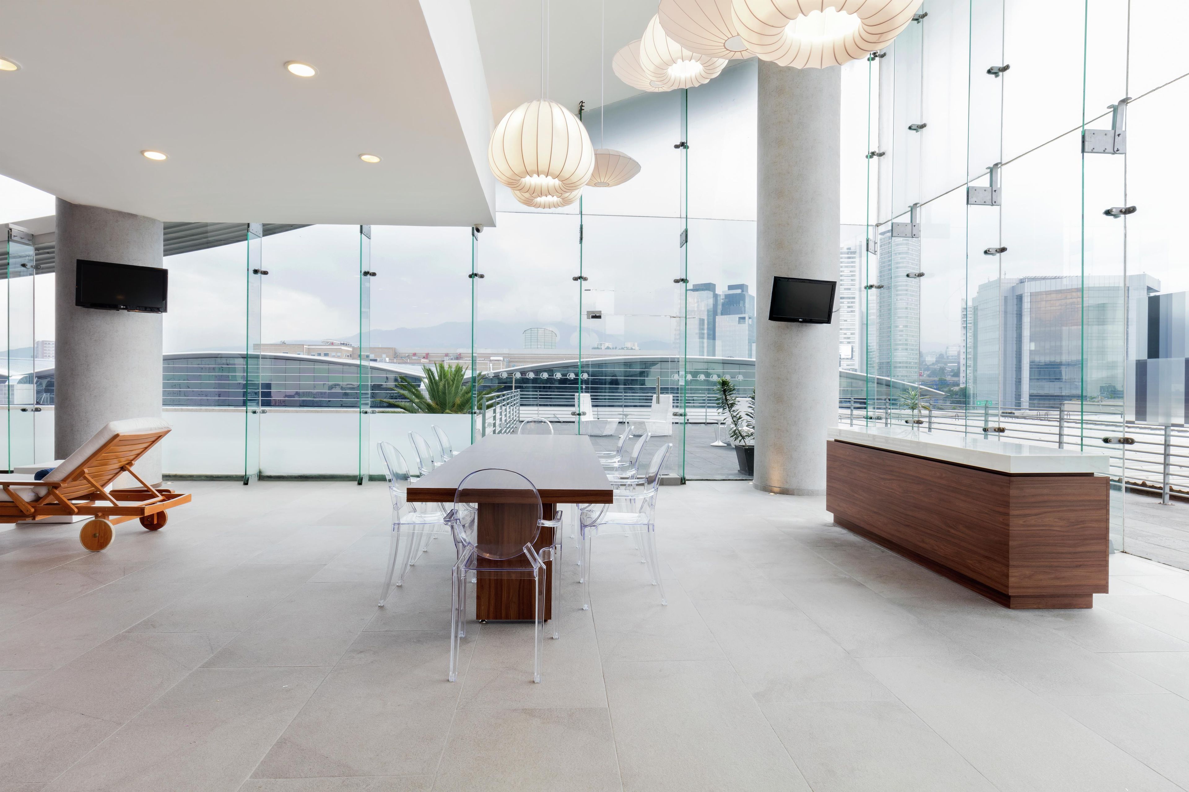 Una sala de conferencias moderna con una amplia mesa, sillas cómodas, un mostrador de recepción de madera y ventanas grandes que ofrecen vistas a la ciudad.
