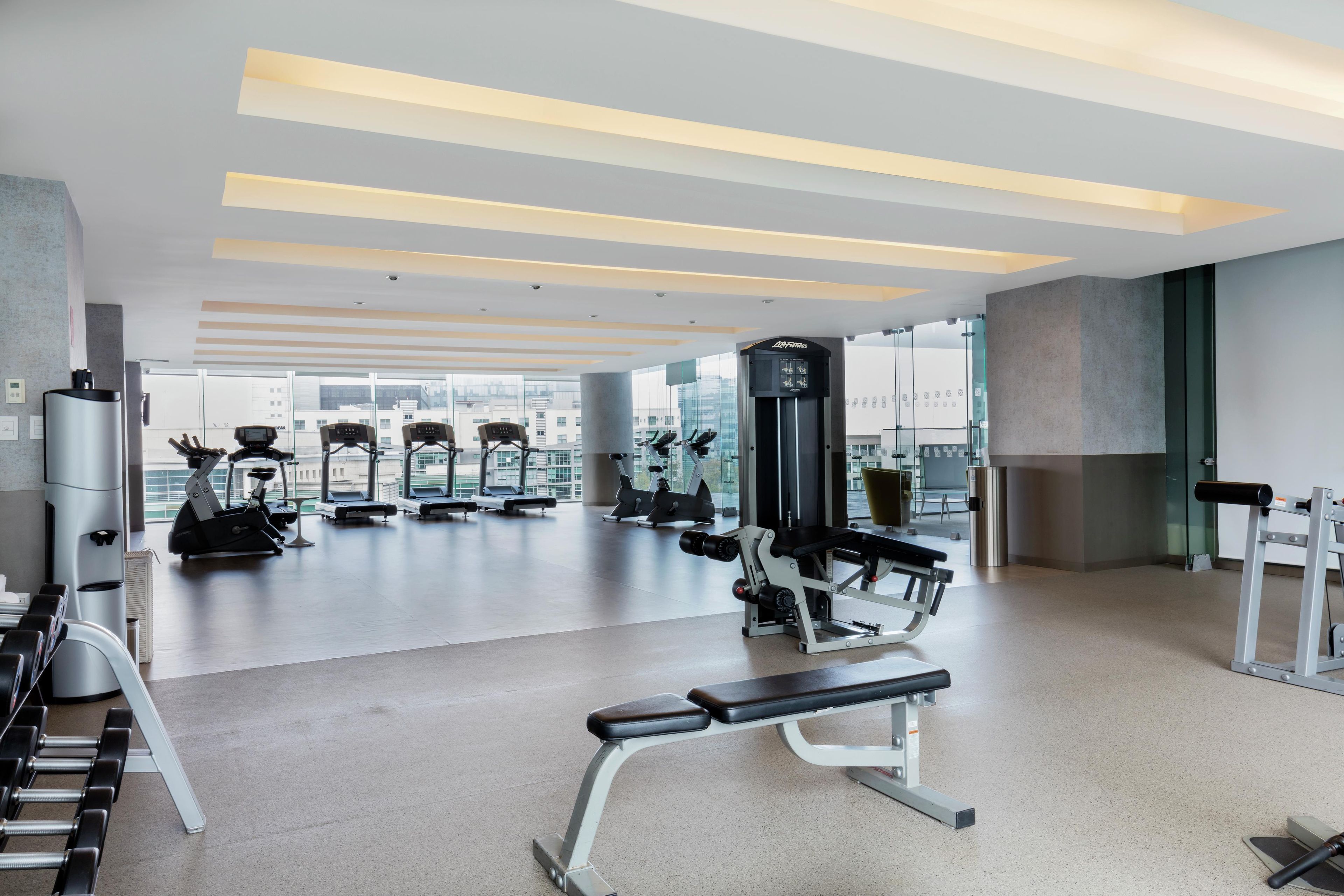 Een moderne sportschool met diverse fitnessapparaten, grote ramen en een ruimtelijke, schone indeling.