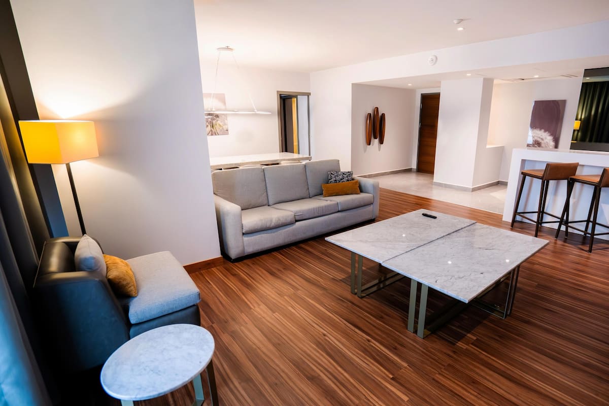 Una sala de estar moderna con un sofá, una mesa de centro, una lámpara y una zona de bar con taburetes.