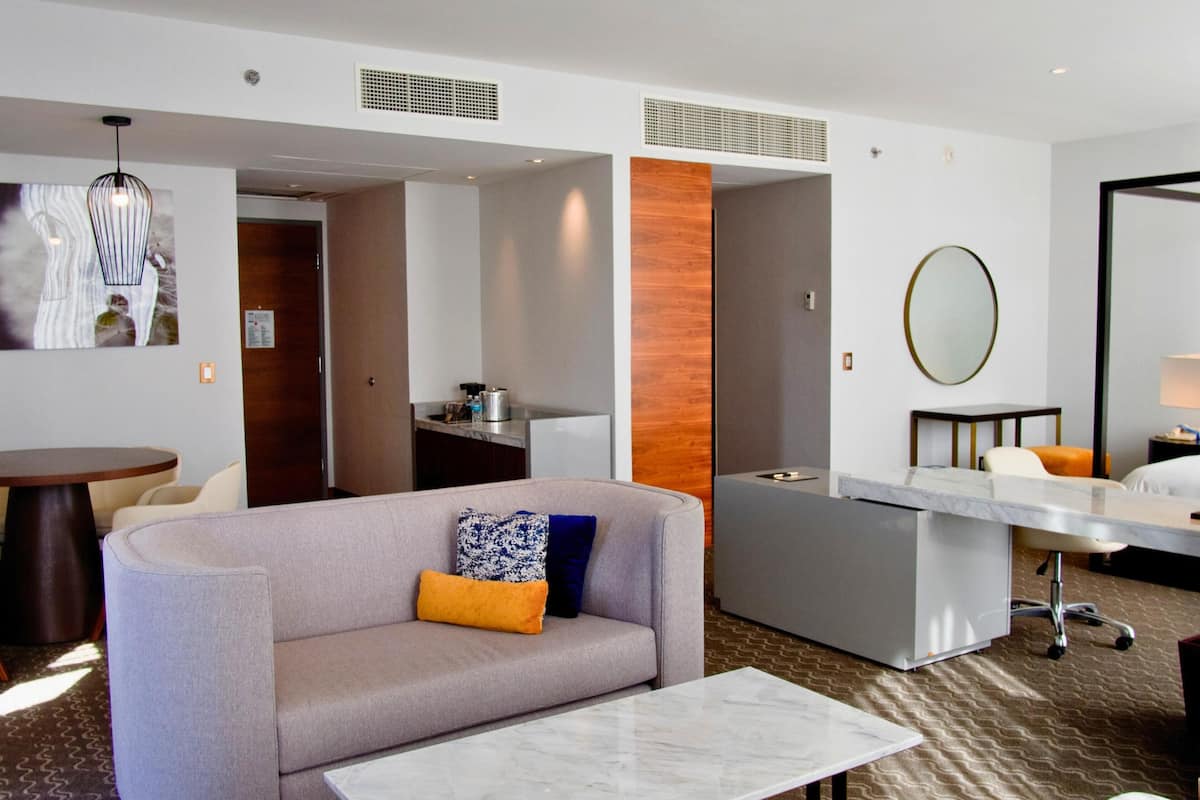 Habitación de hotel con sofá, mesa de comedor, zona de cocina y baño.