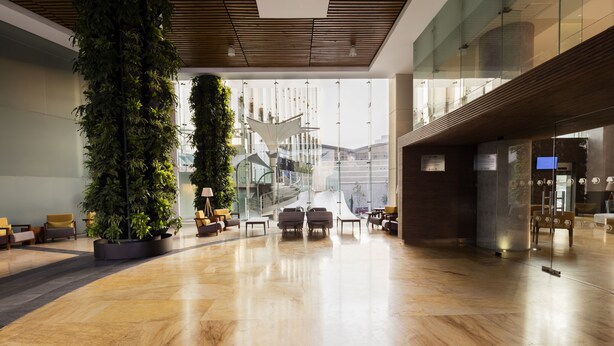 A spacious lobby with a high ceiling, a large vertical garden, and a modern staircase. - DoubleTree by Hilton Hotel Mexico City Santa Fe (Mexico City)