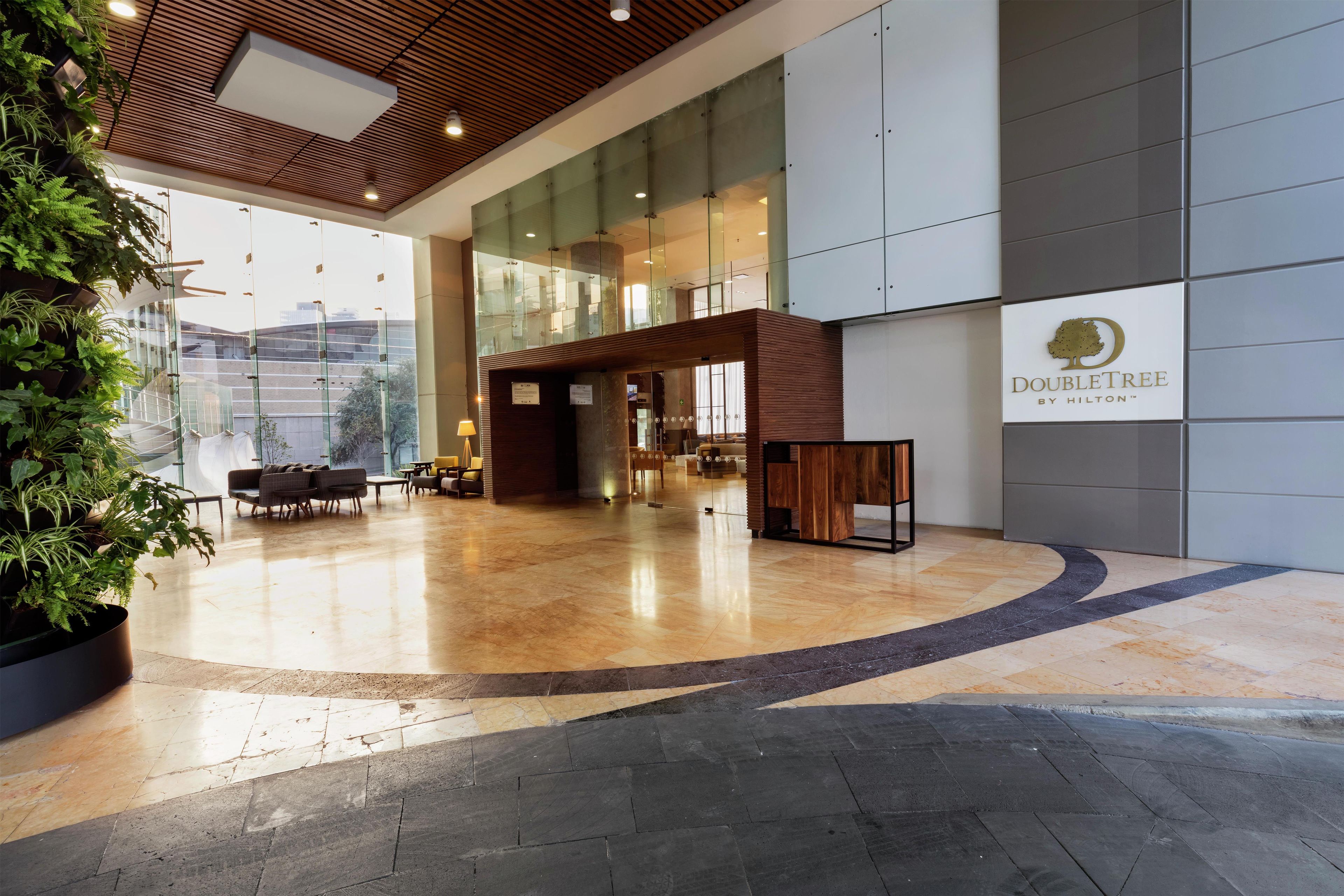 Un vestíbulo de hotel con techo de madera, pared de vidrio y el logotipo de DoubleTree.