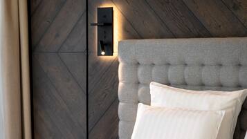 A bedroom with a tufted headboard, a bedside table, and a wall-mounted light fixture.