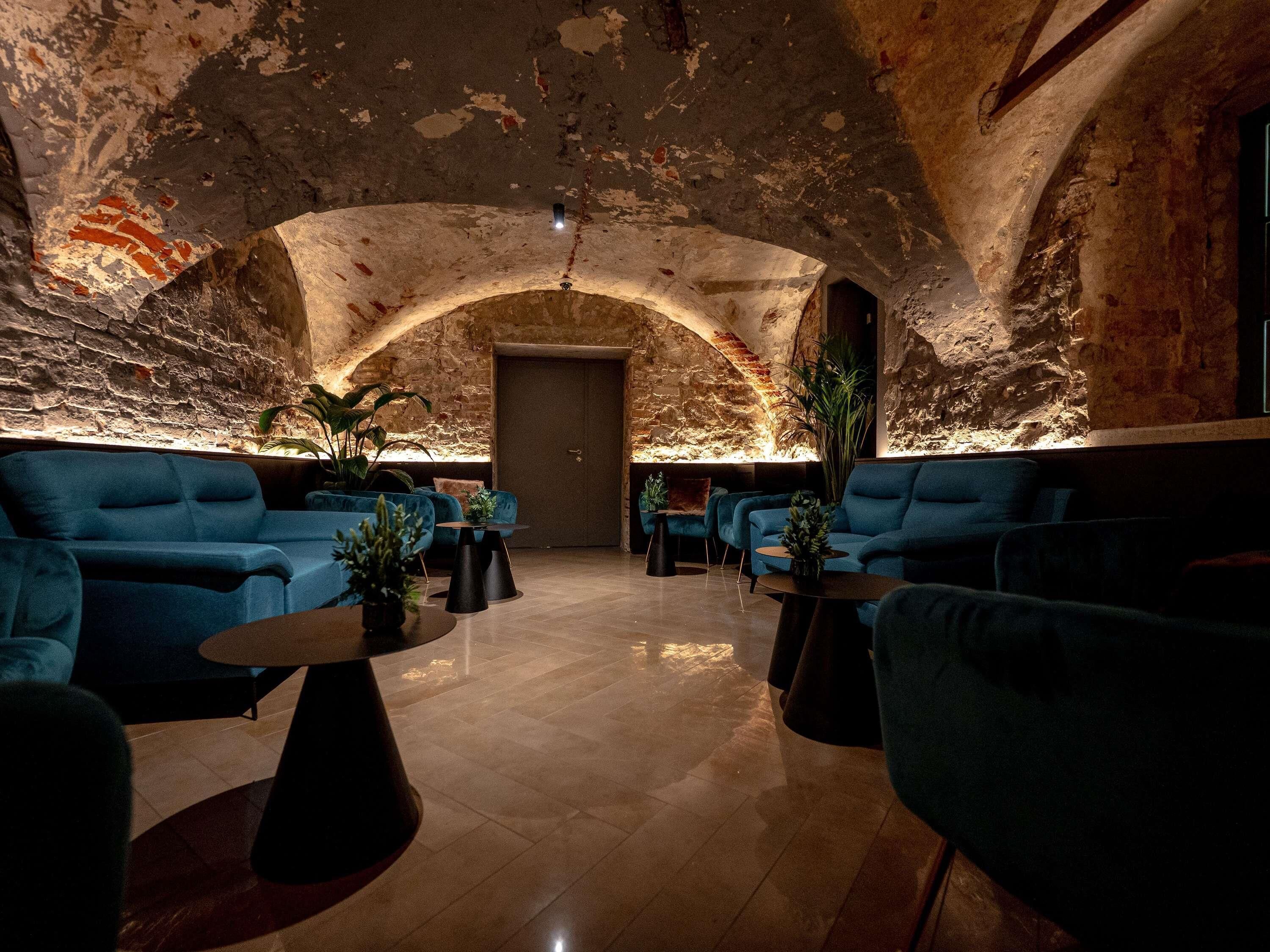 A lounge area with blue sofas, a coffee table, and a stone wall.