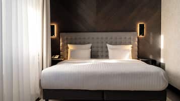 Un dormitorio moderno con una cama grande, un cabecero capitonado y dos lámparas fijadas a la pared.