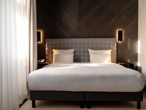 A modern bedroom with a tufted headboard, a large bed with white bedding, and two wall-mounted light fixtures.