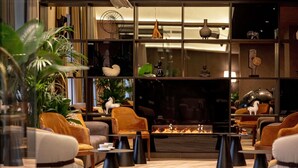 Een moderne zithoek met banken, een open haard en decoratieve items op planken.