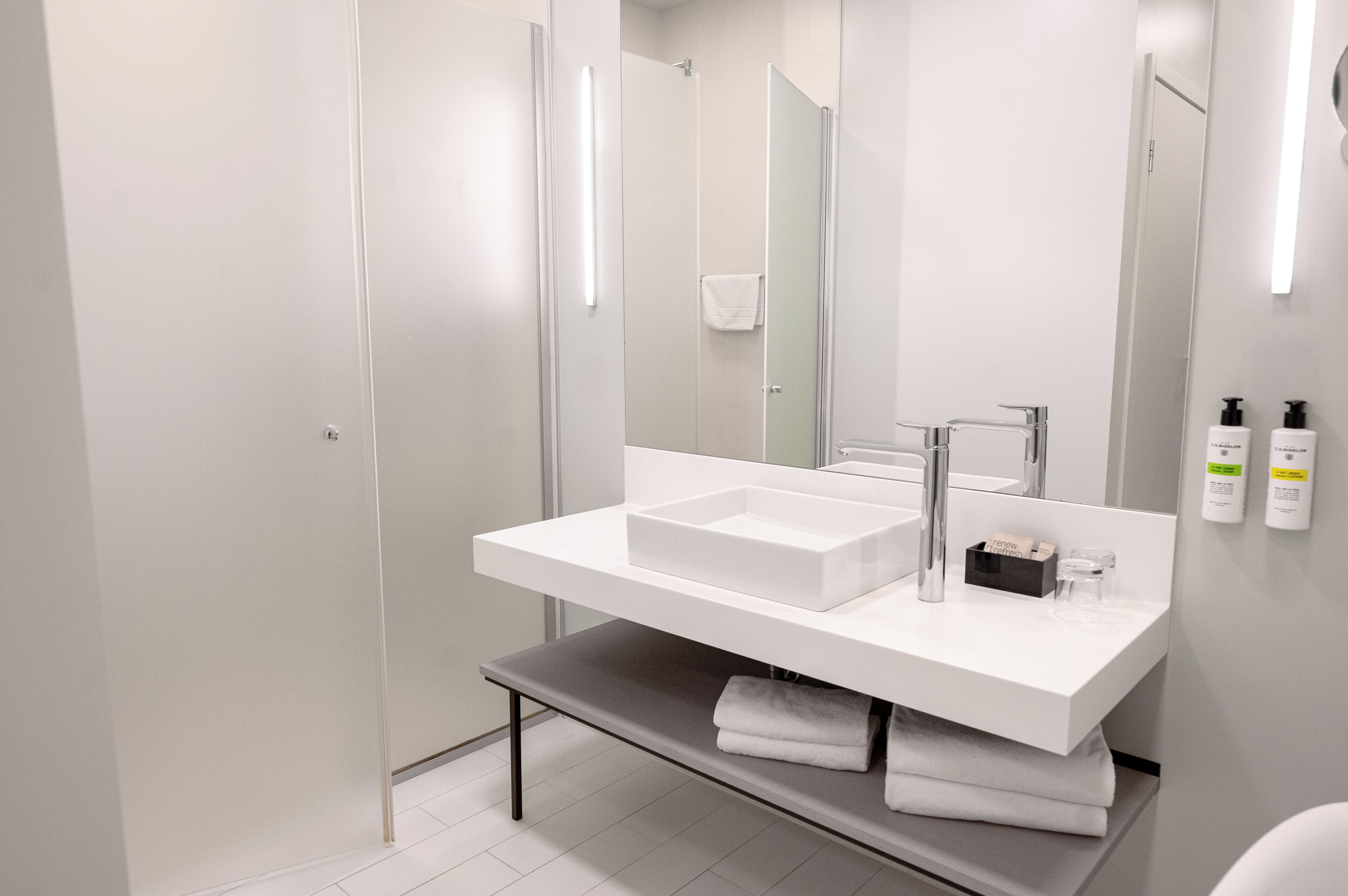 A modern bathroom with a white vanity, a large mirror, and two sinks.