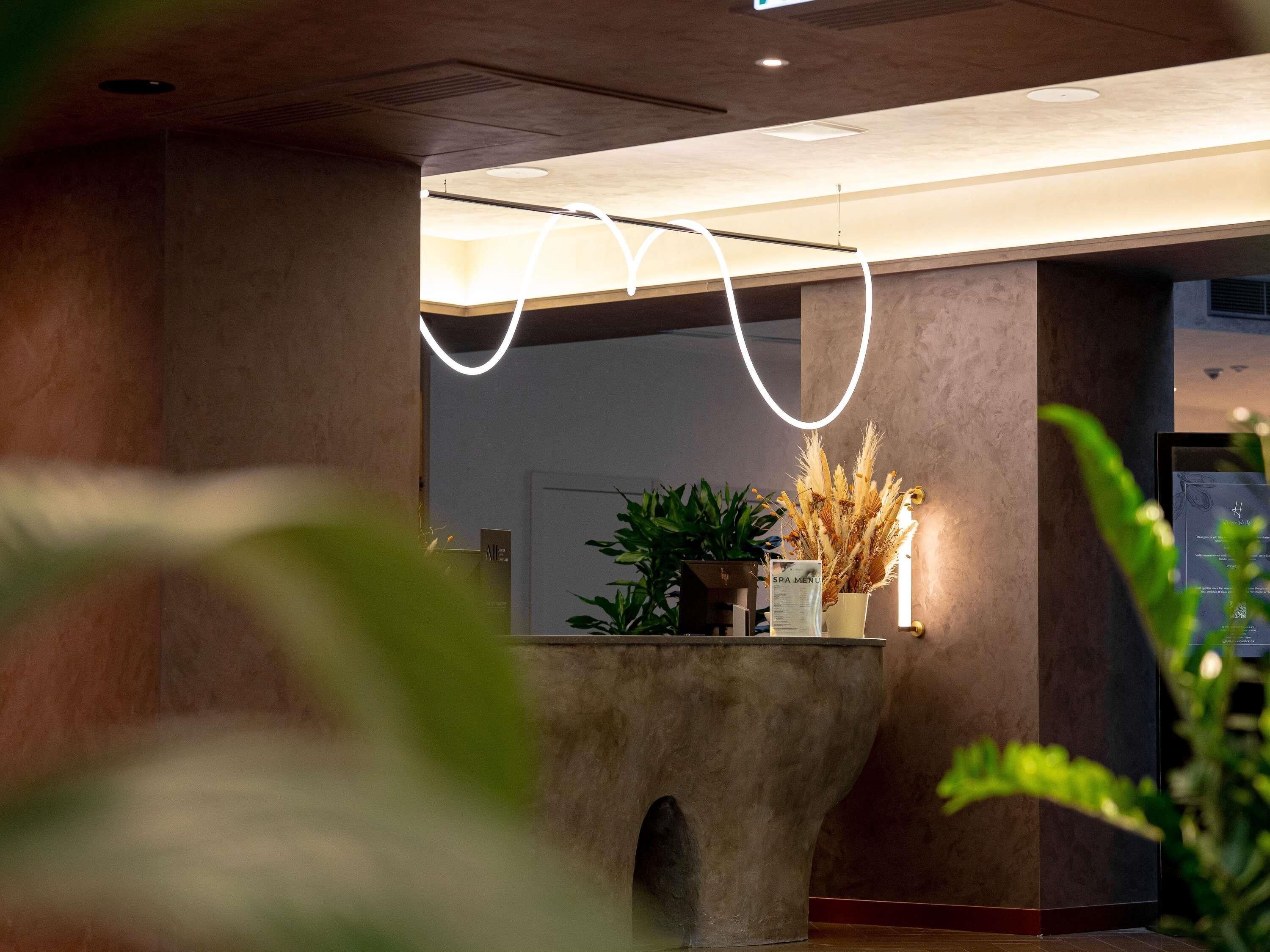 A reception area with a modern design, featuring a concrete planter with plants and a sign labeled "SPA MENU".