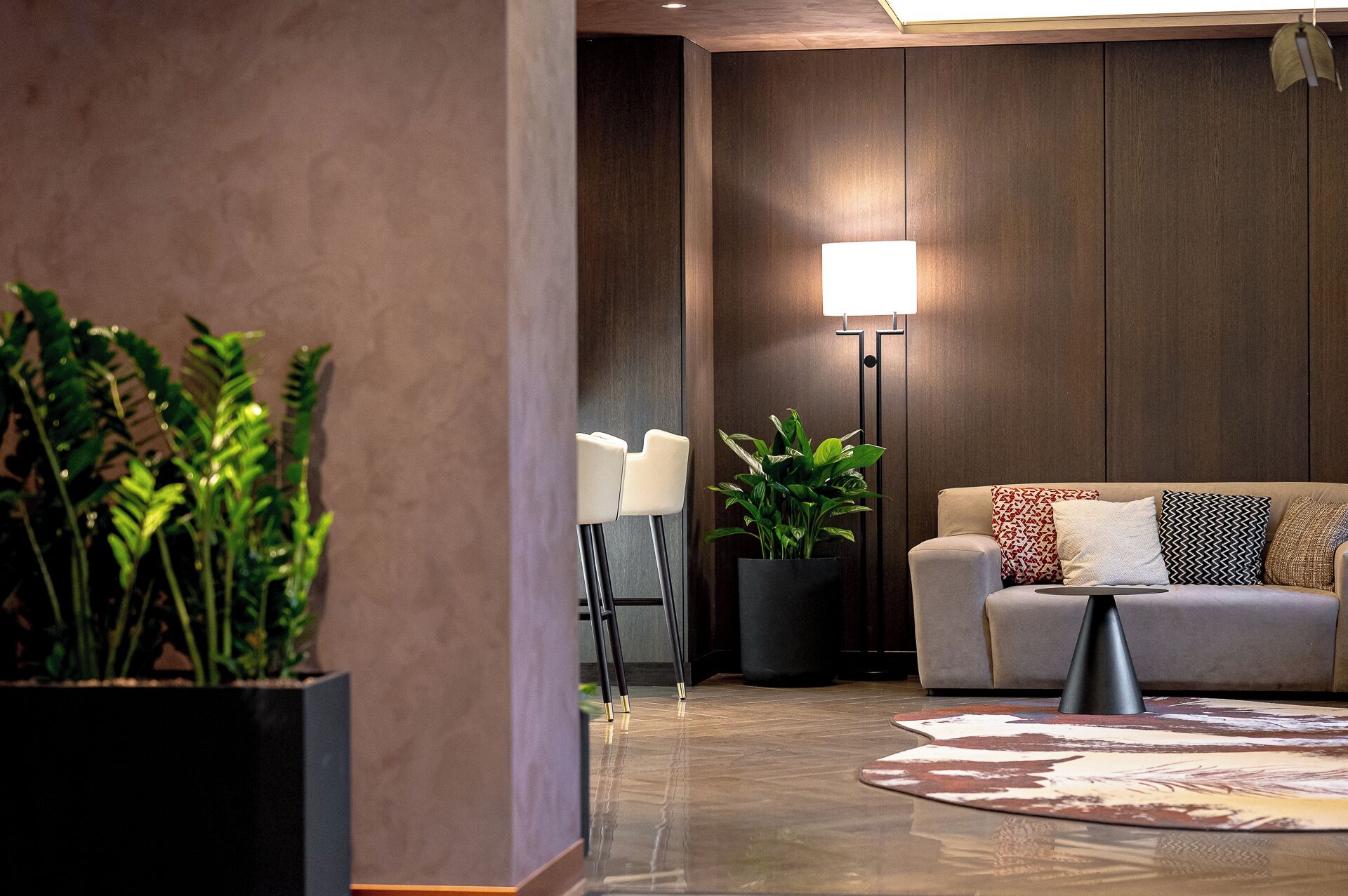 A modern living room with a sofa, a floor lamp, and potted plants.