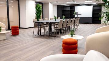 Una sala de reuniones moderna con una mesa larga, sillas y una pantalla para proyector.