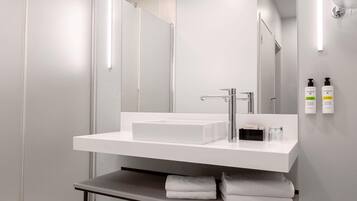 Une salle de bain moderne avec un lavabo blanc, un grand miroir et un porte-serviettes.