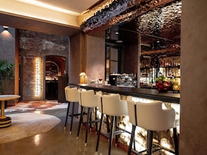 A bar area with a brick wall, a wooden bar counter, and bar stools. - Pullman Riga Old Town (Renovated 2025) (Riga)