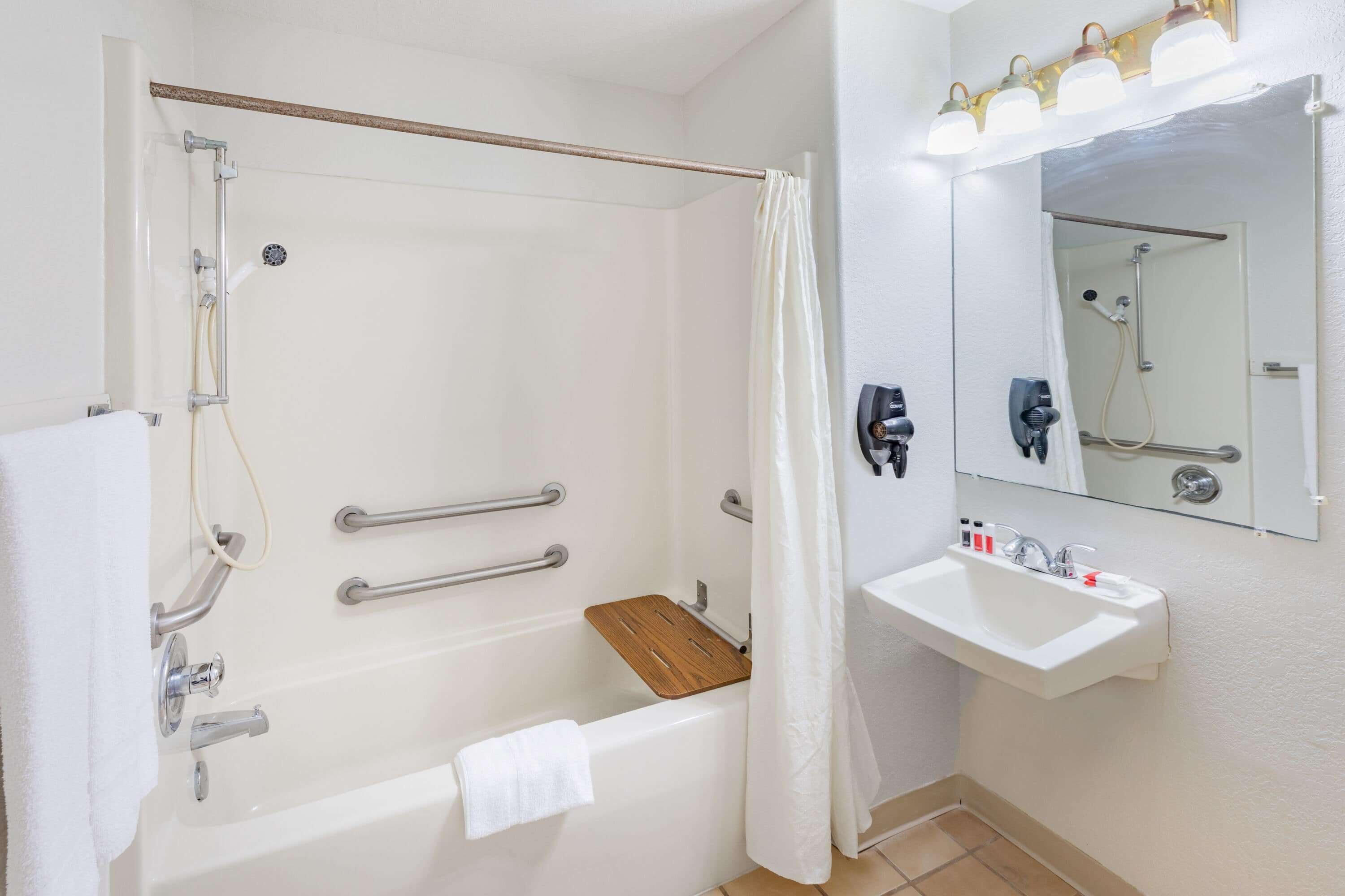 Un baño con bañera, ducha, lavamanos y espejo.
