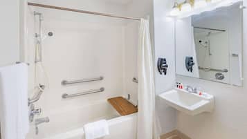 Un baño con bañera, ducha, lavamanos y espejo.