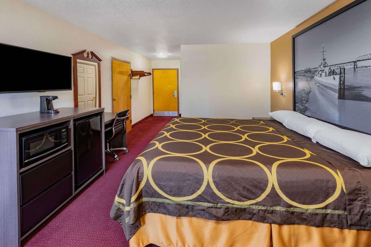 Une chambre d’hôtel équipée d’un lit, d’un bureau, d’une télévision, d’un four à micro-ondes et d’une porte.