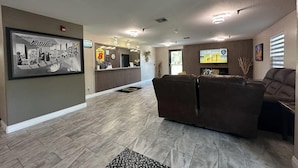 A lobby with a reception desk, a brown leather sofa, and a framed Kinder chocolate advertisement. - Super 8 by Wyndham Kinder/Coushatta near Casino (Kinder)