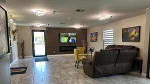 A spacious living area with a fireplace, a sofa, a yellow armchair, and a television. - Super 8 by Wyndham Kinder/Coushatta near Casino (Kinder)