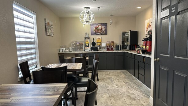 A modern kitchen with a dining area, featuring a marble countertop, dark cabinetry, and a 'STAFF ONLY' door. - Super 8 by Wyndham Kinder/Coushatta near Casino (Kinder)