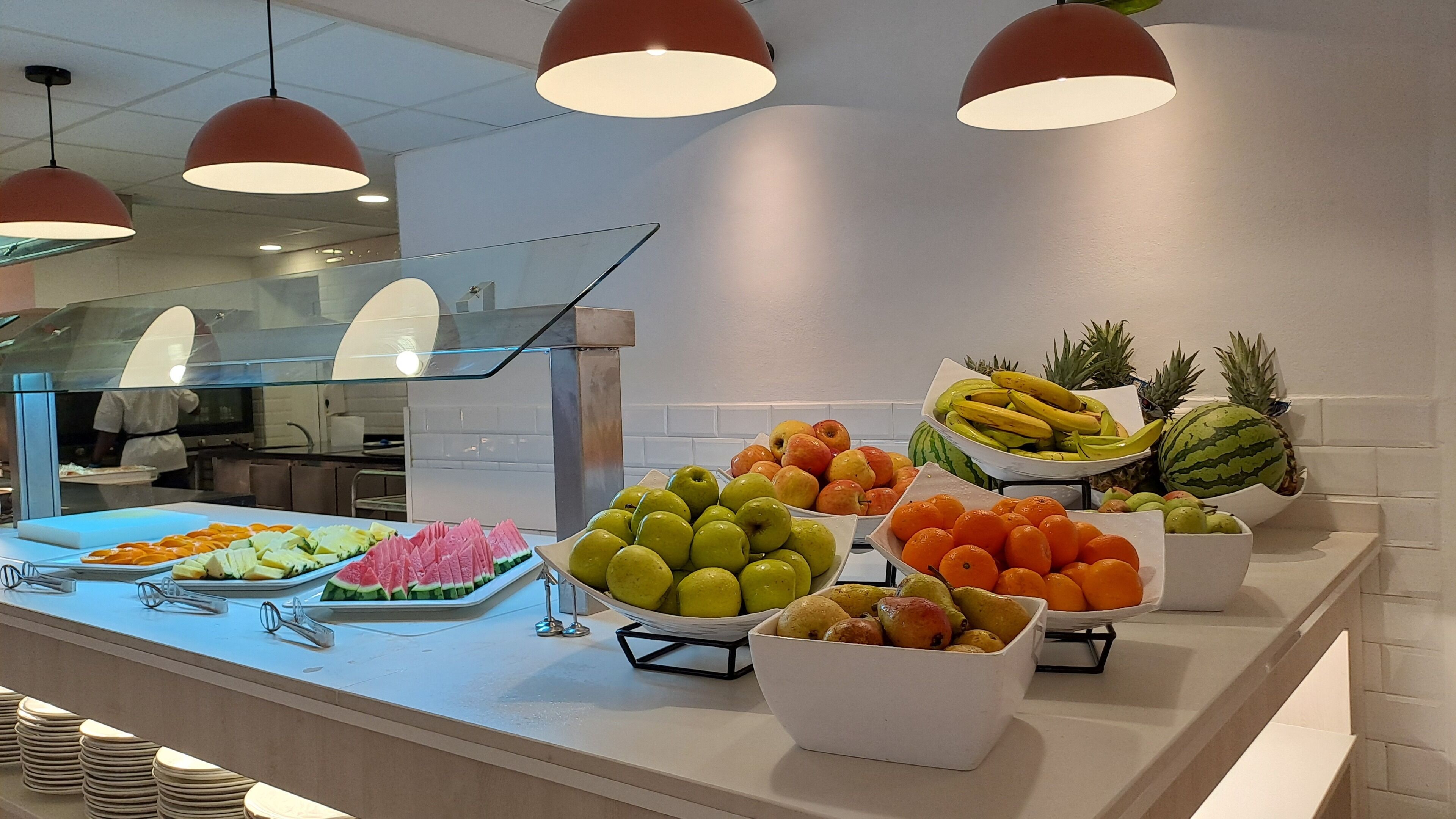 Un buffet proposant une variété de fruits et de légumes, notamment des pommes, des oranges et des pastèques.