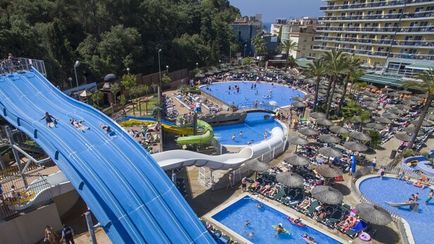 Parque acuático con varias piscinas y un tobogán de agua grande.
