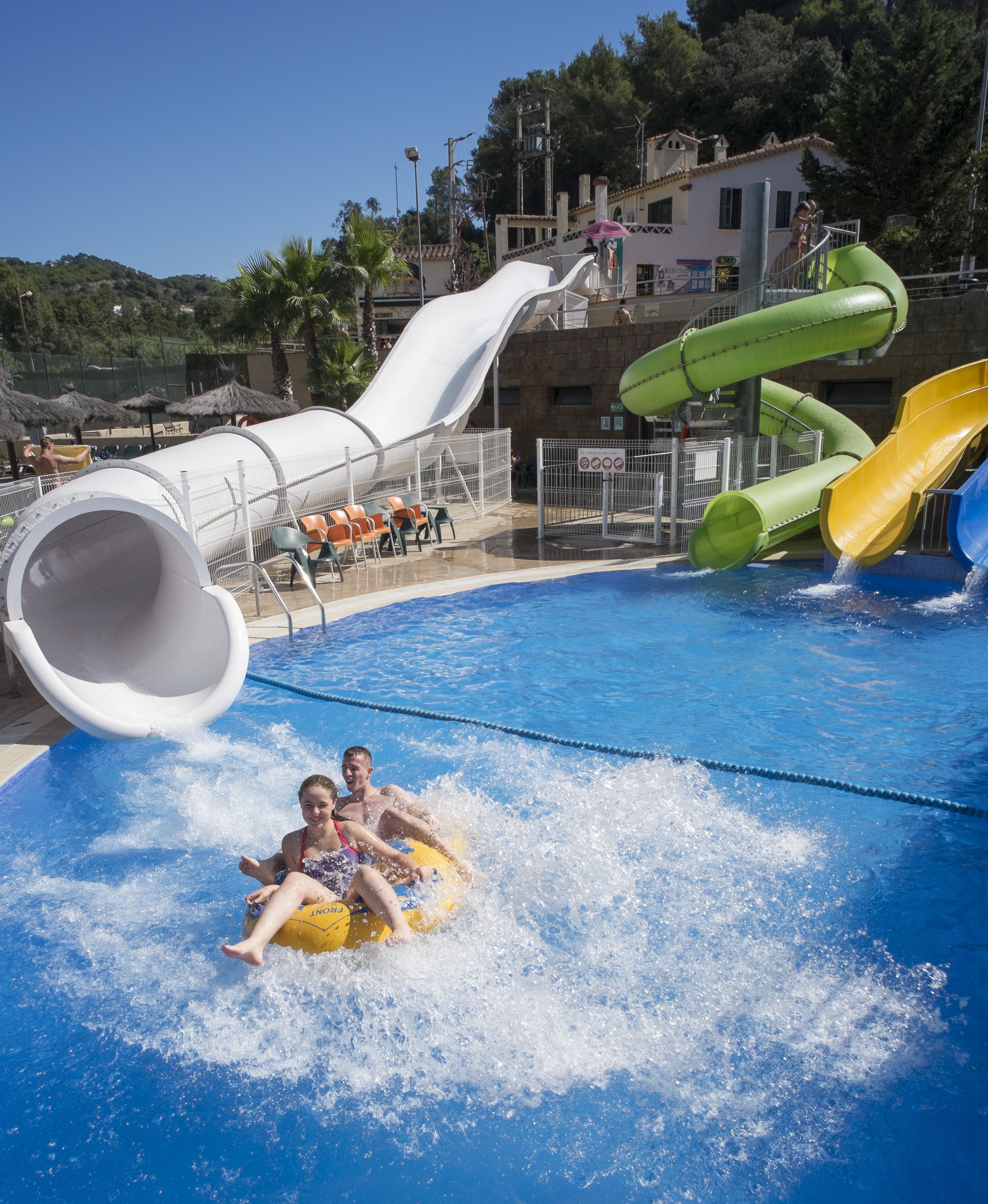 Ein Wasserpark mit Pool, Rutschen und Sitzbereichen.