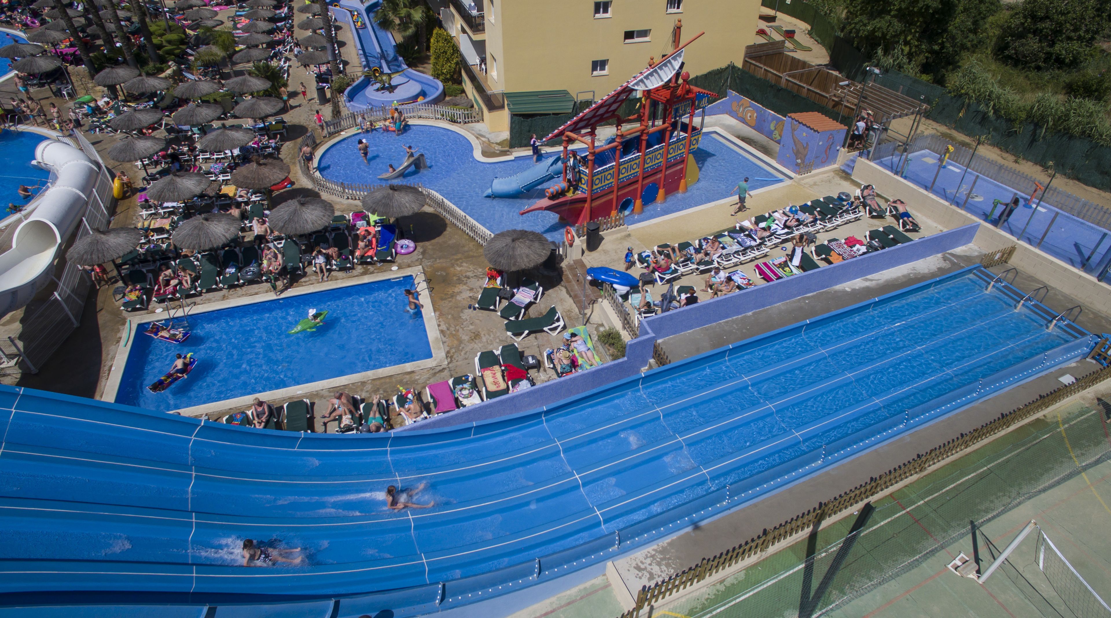 Luchtbeeld van een waterpark met meerdere zwembaden, glijbanen en ontspanningszones.
